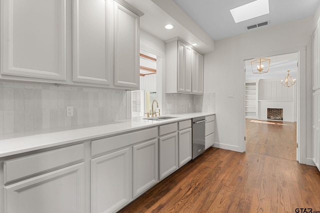 kitchen with sink, dishwasher, tasteful backsplash, a fireplace, and dark hardwood / wood-style flooring