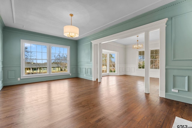 unfurnished dining area featuring ornamental molding, a notable chandelier, and dark hardwood / wood-style flooring