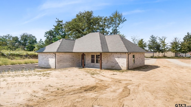 exterior space with brick siding and a shingled roof