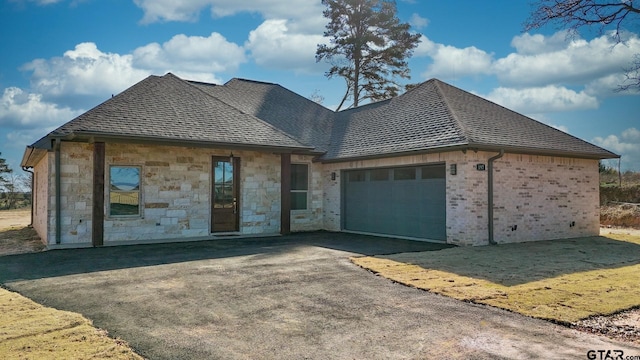 view of front of home with an attached garage, driveway, and roof with shingles