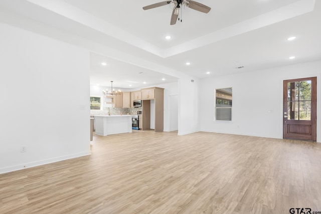 unfurnished living room featuring ceiling fan with notable chandelier, recessed lighting, light wood-type flooring, and baseboards