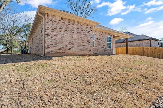 view of side of home featuring a yard and central AC