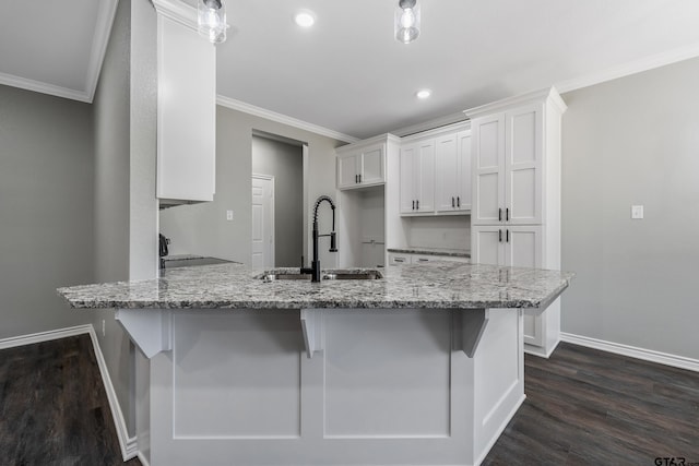 kitchen with white cabinetry, light stone counters, kitchen peninsula, and sink