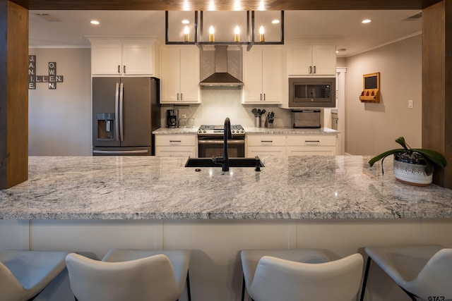 kitchen with wall chimney exhaust hood, white cabinetry, stainless steel appliances, and a breakfast bar area