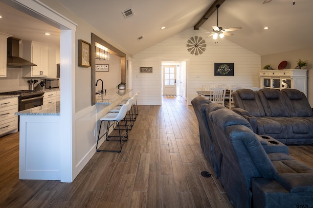 living room featuring sink, wood walls, lofted ceiling with beams, dark hardwood / wood-style floors, and ceiling fan