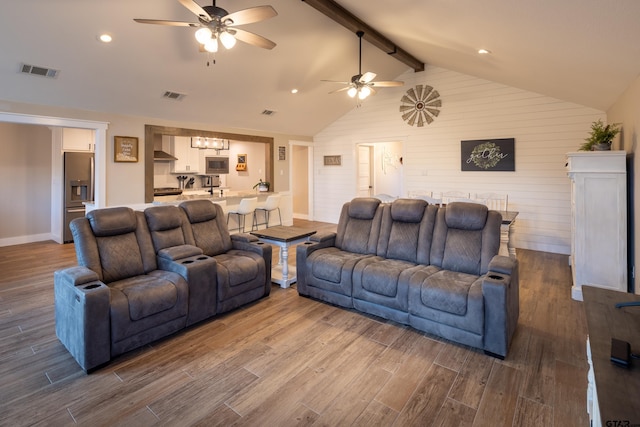 living room with ceiling fan, wooden walls, and vaulted ceiling with beams