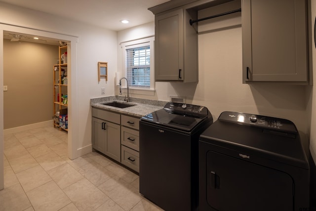 clothes washing area with cabinets, washer and clothes dryer, and sink