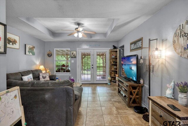 12305 Pine St, Larue, TX 75770 - living room with a textured ceiling, light tile patterned floors, ceiling fan, french doors, and a tray ceiling