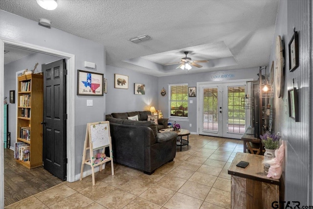 12305 Pine St, Larue, TX 75770 - living area featuring a tray ceiling, a ceiling fan, french doors, light tile patterned flooring, and a textured ceiling