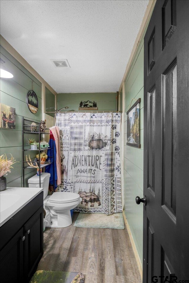 12305 Pine St, Larue, TX 75770 - full bathroom with wood finished floors, a textured ceiling, a shower with curtain, toilet, and visible vents