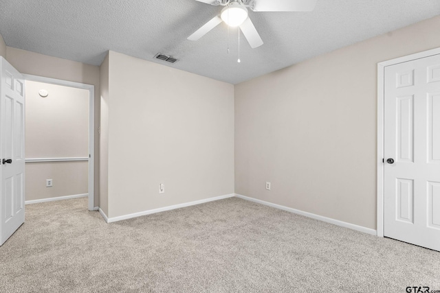 unfurnished bedroom with light carpet, a textured ceiling, and ceiling fan