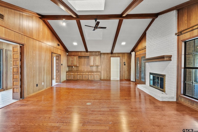 unfurnished living room featuring wood walls, lofted ceiling with beams, and light hardwood / wood-style floors