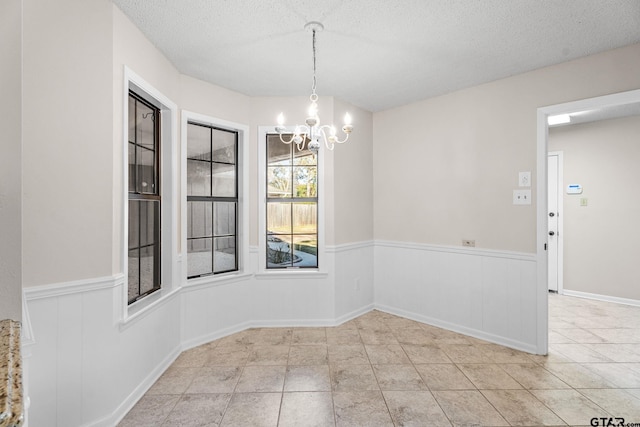 unfurnished dining area featuring light tile patterned floors, a textured ceiling, and a notable chandelier