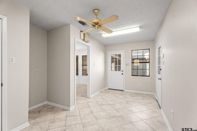 tiled foyer entrance with ceiling fan and a textured ceiling