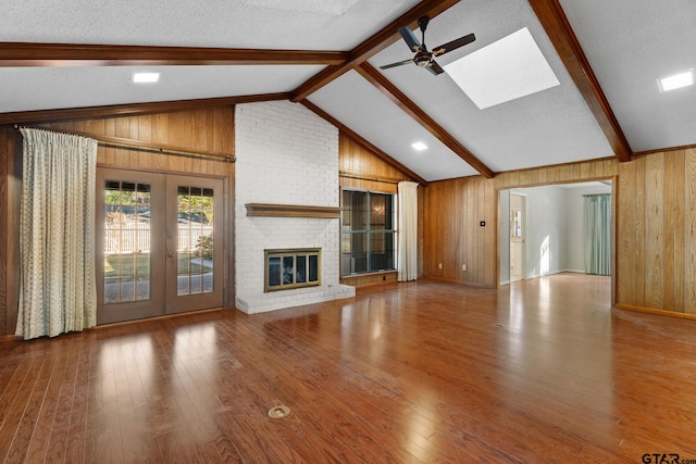 unfurnished living room with lofted ceiling with beams, wood walls, wood-type flooring, and a textured ceiling