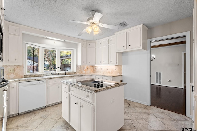 kitchen with a kitchen island, sink, light tile patterned floors, dishwasher, and white cabinetry