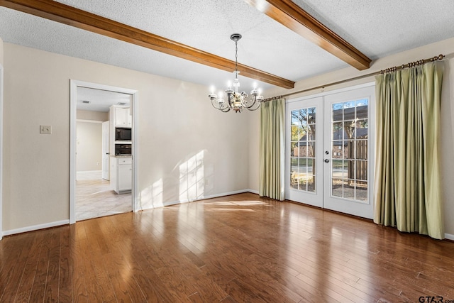 unfurnished dining area featuring hardwood / wood-style floors, french doors, beamed ceiling, and a textured ceiling