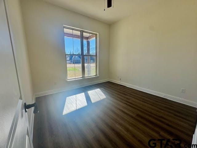 empty room with ceiling fan and dark hardwood / wood-style flooring