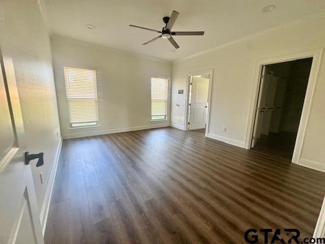 unfurnished bedroom with dark hardwood / wood-style flooring, ornamental molding, ceiling fan, a spacious closet, and a closet