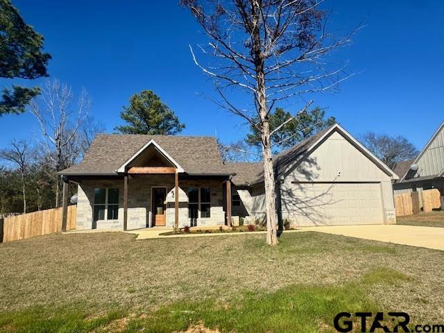 view of front of property with covered porch, a garage, and a front yard