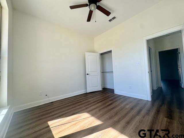 unfurnished bedroom with ceiling fan, dark hardwood / wood-style flooring, and a closet