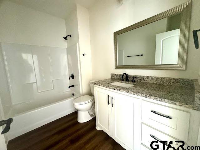 full bathroom with shower / tub combination, vanity, hardwood / wood-style flooring, and toilet