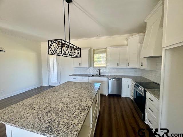 kitchen with pendant lighting, dark wood-type flooring, appliances with stainless steel finishes, a kitchen island, and white cabinetry