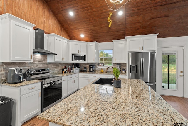 kitchen featuring white cabinetry, wall chimney range hood, stainless steel appliances, and vaulted ceiling