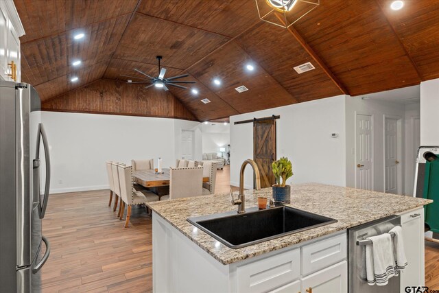 kitchen with appliances with stainless steel finishes, a barn door, white cabinetry, and sink