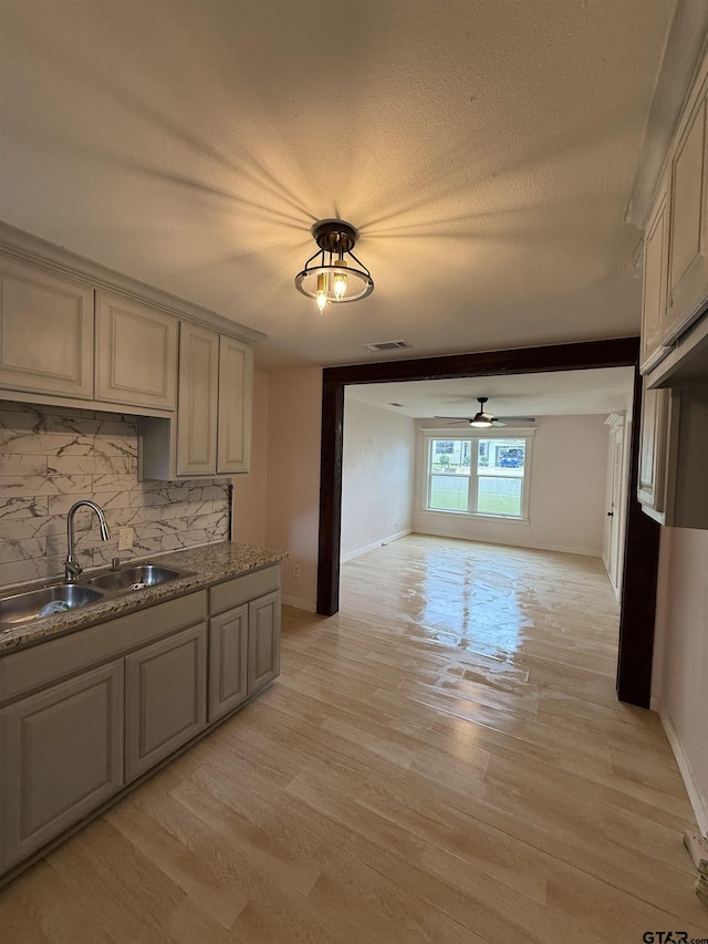 2907 Cushing Dr, Tyler, TX 75702 - kitchen with tasteful backsplash, a ceiling fan, light wood-style floors, gray cabinets, and a textured ceiling