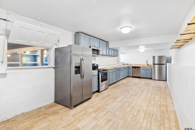 4456 Fm 2767, Tyler, TX 75708 - kitchen featuring stainless steel appliances, light wood finished floors, a sink, light countertops, and blue cabinetry