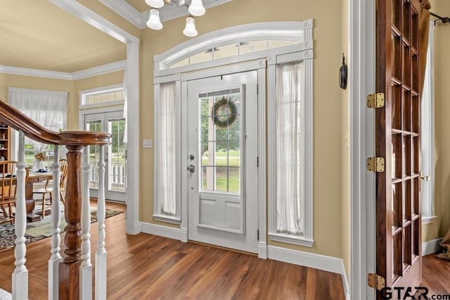 entrance foyer featuring wood finished floors, crown molding, and a notable chandelier