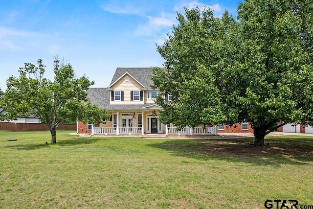 view of front of house featuring a front lawn, a shingled roof, covered porch, french doors, and fence