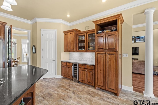 kitchen featuring dark stone countertops, tasteful backsplash, brown cabinets, crown molding, and wine cooler
