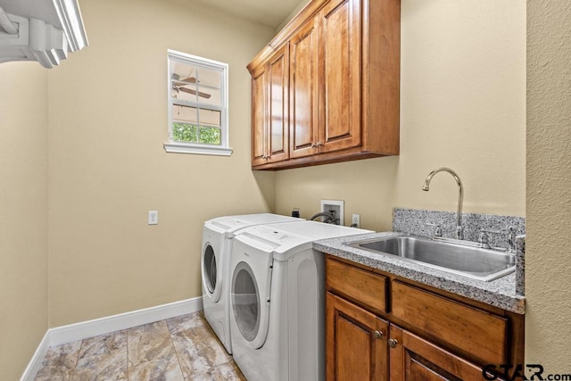 washroom featuring stone finish floor, a sink, baseboards, separate washer and dryer, and cabinet space