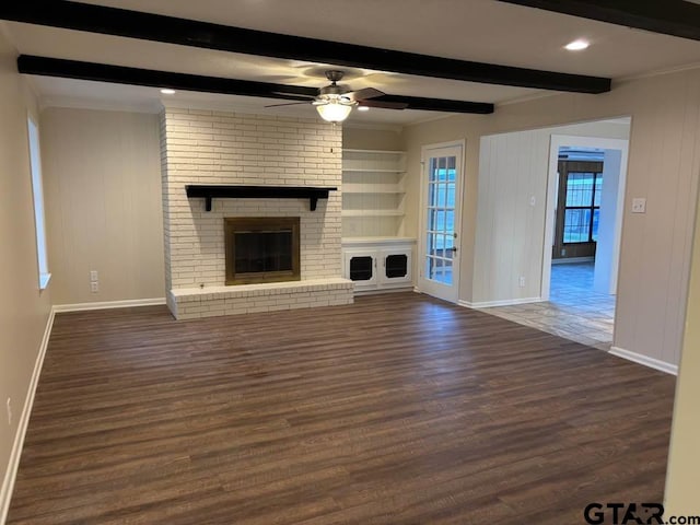 unfurnished living room with beamed ceiling, a brick fireplace, dark hardwood / wood-style floors, and ceiling fan