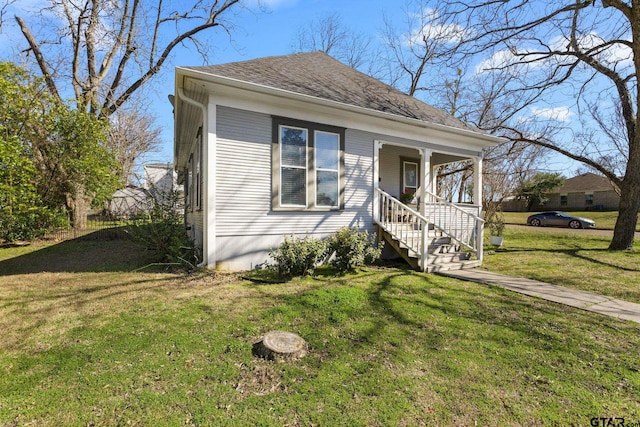 bungalow with covered porch, roof with shingles, and a front yard