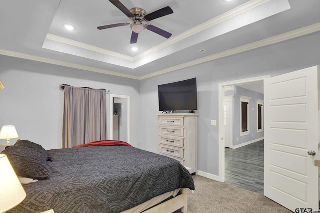 carpeted bedroom with ceiling fan, ornamental molding, and a tray ceiling