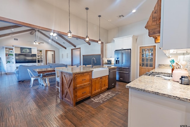 kitchen with a sink, dark wood finished floors, stainless steel appliances, open floor plan, and beamed ceiling