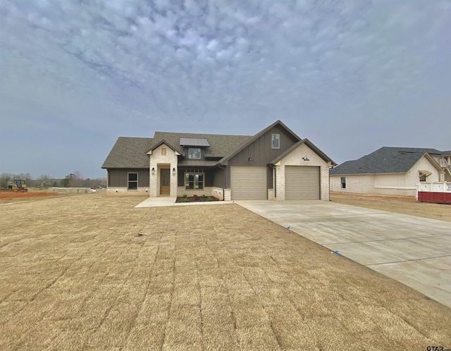 view of front facade featuring driveway, roof with shingles, board and batten siding, an attached garage, and brick siding