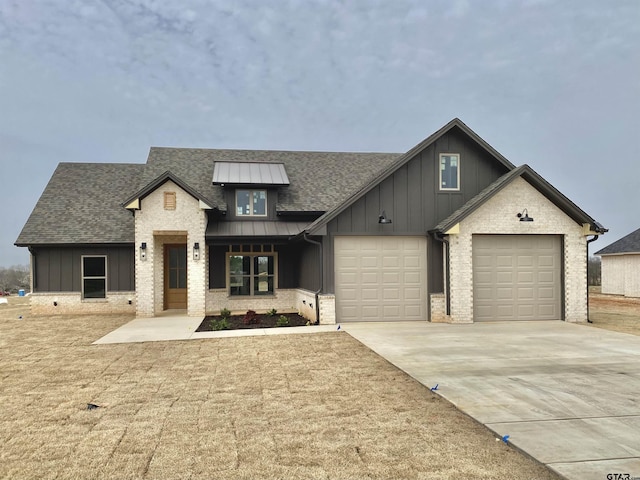 view of front of house with a standing seam roof, a garage, board and batten siding, and driveway