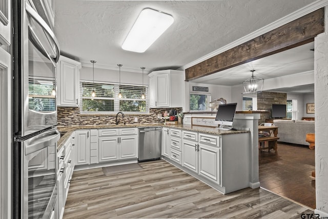 kitchen featuring hanging light fixtures, white cabinetry, appliances with stainless steel finishes, and kitchen peninsula