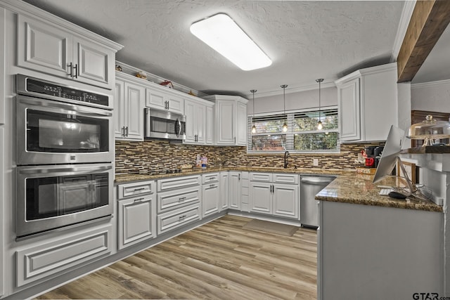 kitchen featuring white cabinetry, stainless steel appliances, tasteful backsplash, ornamental molding, and light wood-type flooring