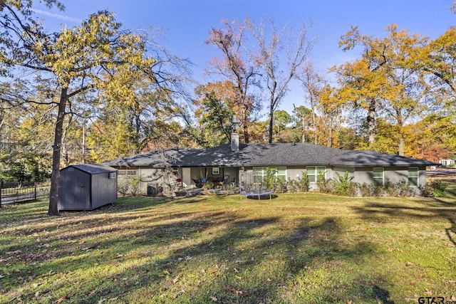 rear view of house featuring a trampoline, a shed, and a lawn