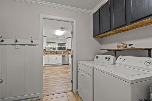 laundry room with sink, crown molding, light tile patterned floors, washing machine and dryer, and cabinets