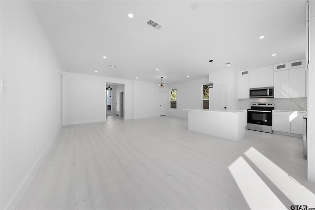 kitchen featuring a center island, light hardwood / wood-style flooring, hanging light fixtures, white cabinetry, and appliances with stainless steel finishes