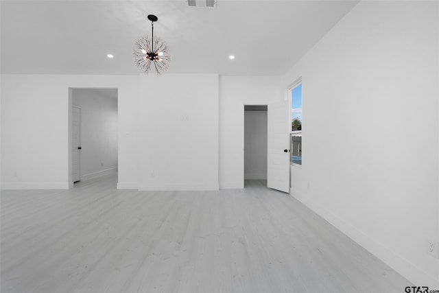 spare room featuring light hardwood / wood-style floors and a notable chandelier