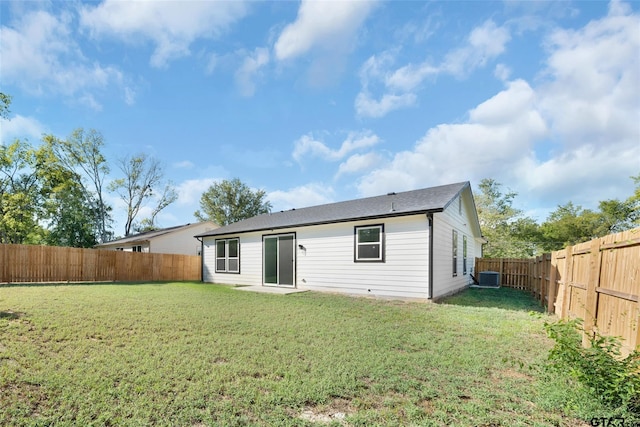 rear view of property featuring central air condition unit and a yard