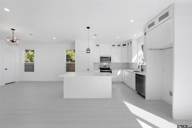 kitchen featuring white cabinetry, pendant lighting, a center island, and stainless steel appliances