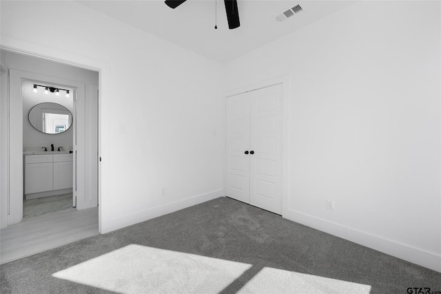 spare room featuring dark colored carpet, ceiling fan, and sink